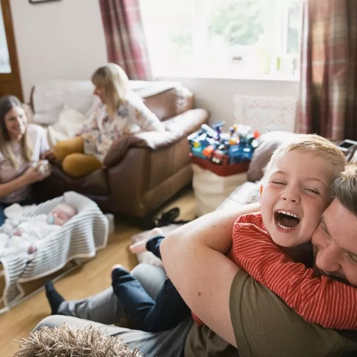 man hugging young boy happy family scene at home