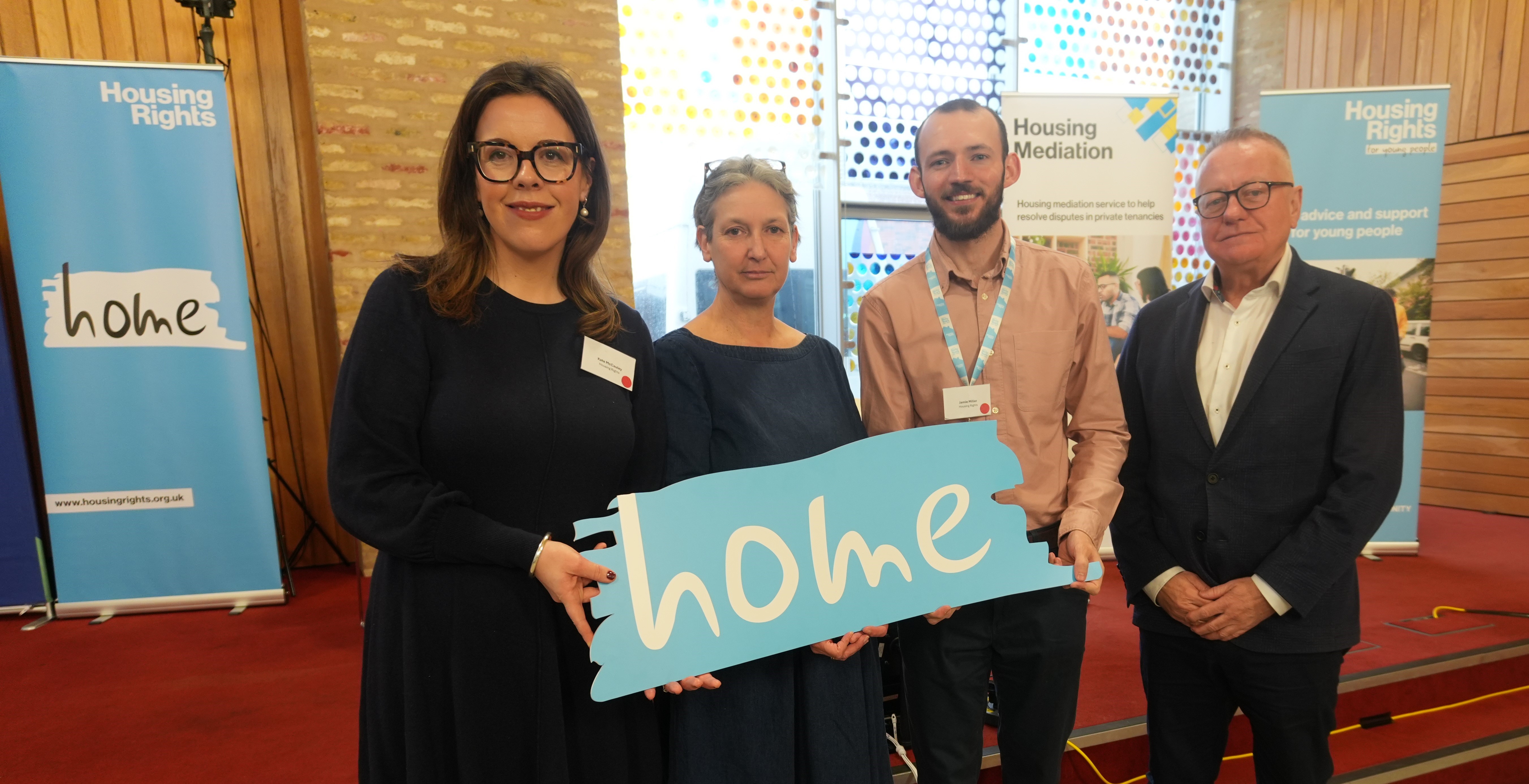 Kate, Dr Julie Rugg, Jamie Miller, Paddy Gray holding the "Home" sign