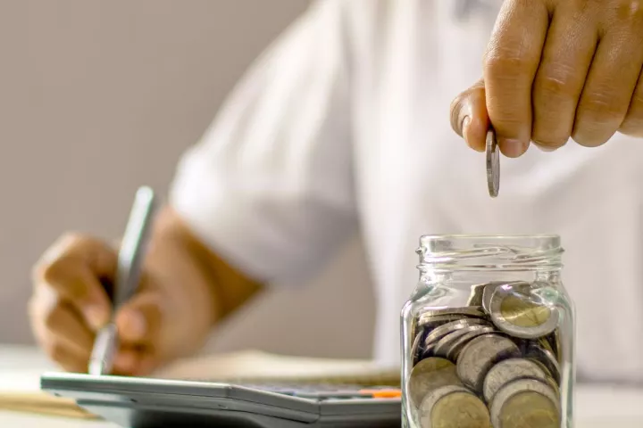 Man putting money into a jar