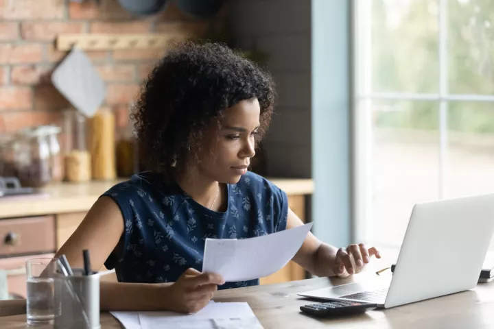 Image of a woman in front of computer with a calculator