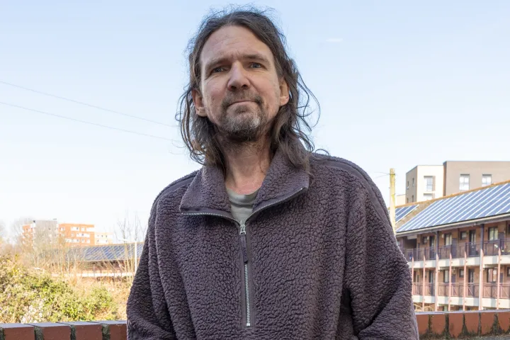 A man called Mathew stands against a wall looking at the camera