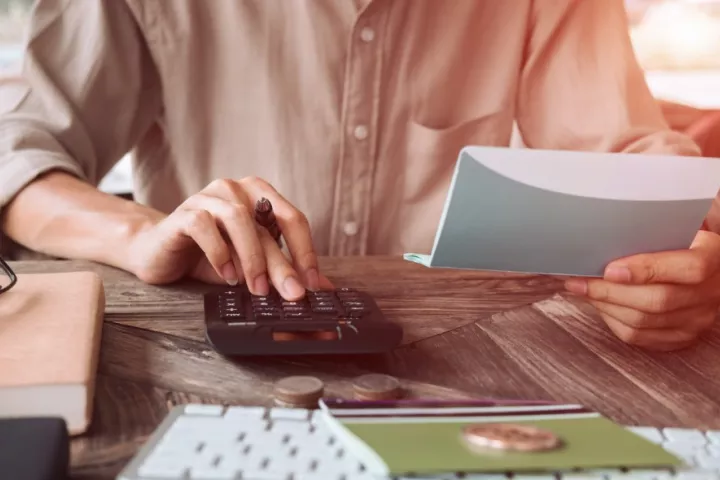 Man checking a bank statement using a calculator