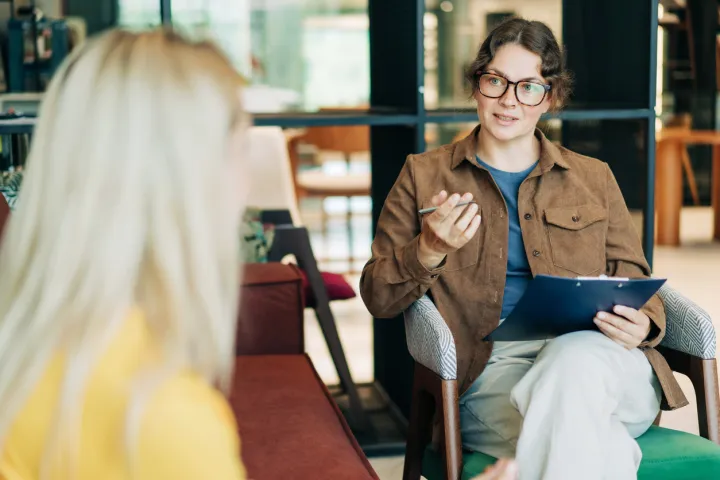 person sitting in chair chatting to another person