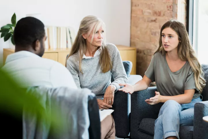 Three people sit around discussing