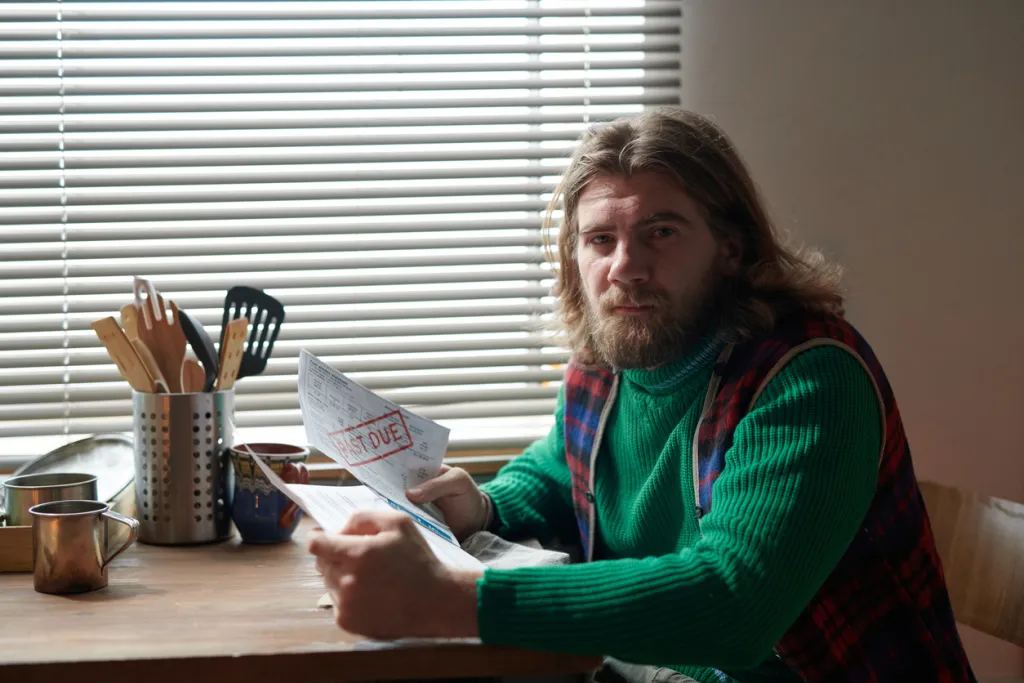 Man sitting at the table with past due bills in hand