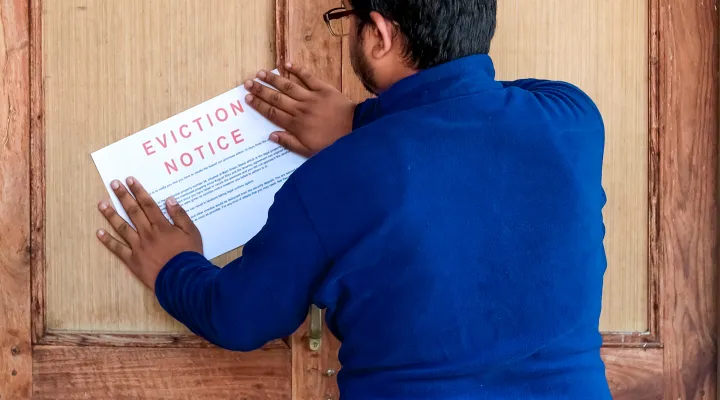 Man in blue top pins notice to quit on a door